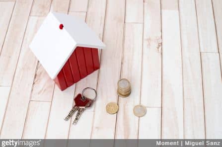 Petite maison en bois avec des clés et des pièces de monnaie