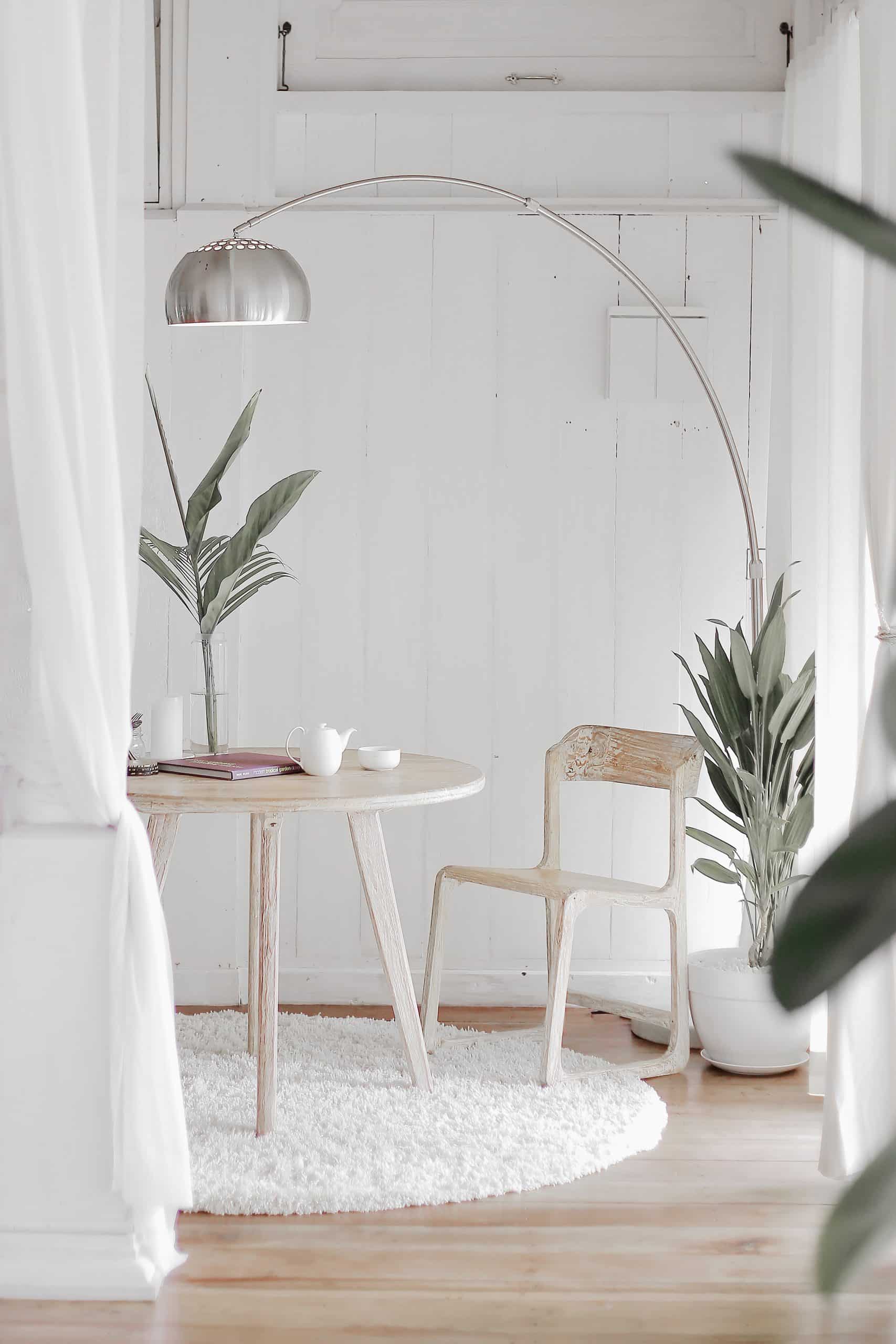 pièce décorée en blanc avec parquet au sol table e t chaise en bois luminaire et plantes
