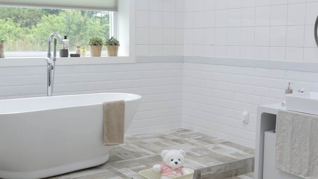 salle de bain avec baignoire carrelage mural blanc et sol effet parquet